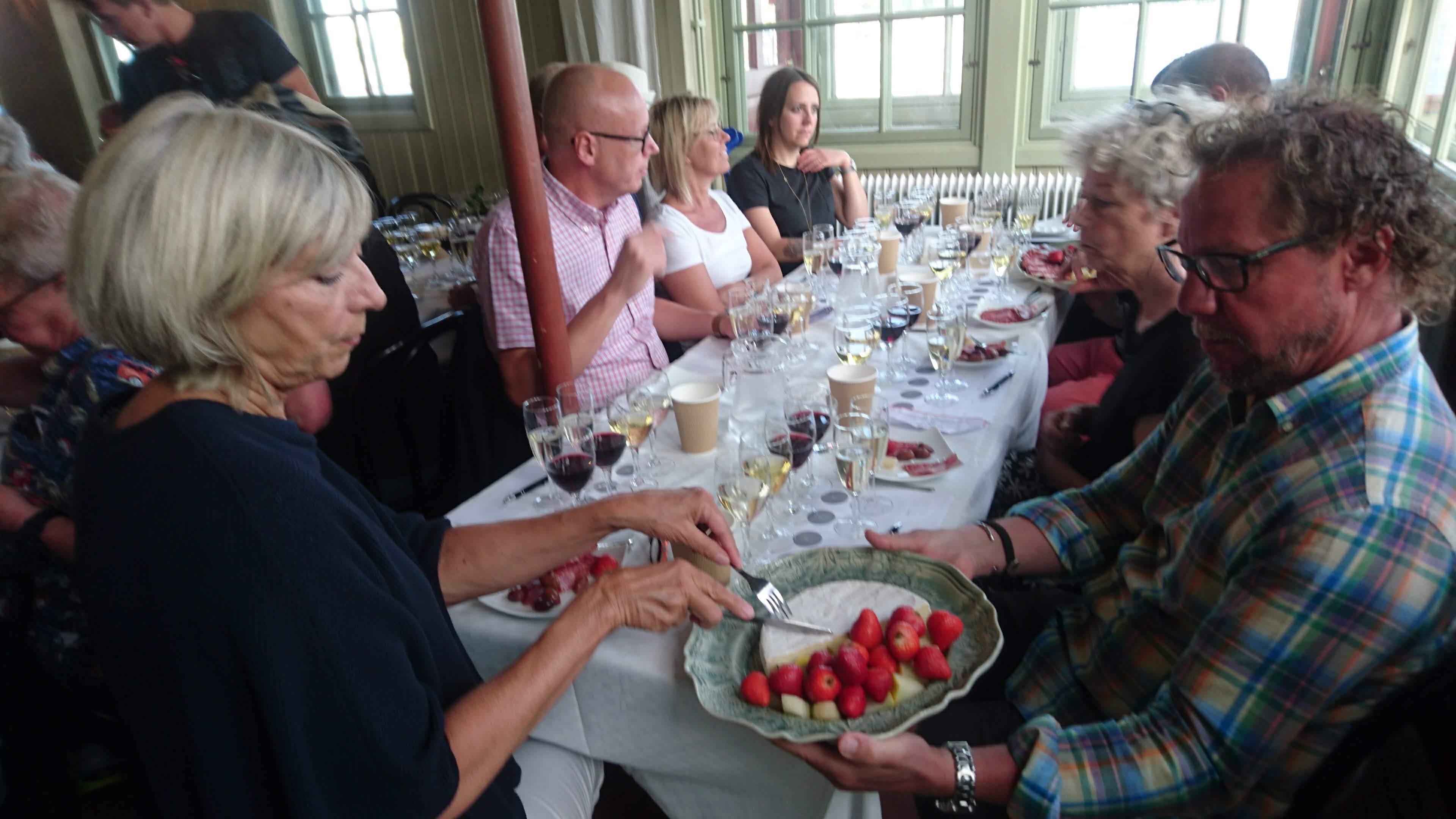 Glada festdeltagare vid festdukade bord. Vinprovning med våra gäster från Helgolands badeanstalt 